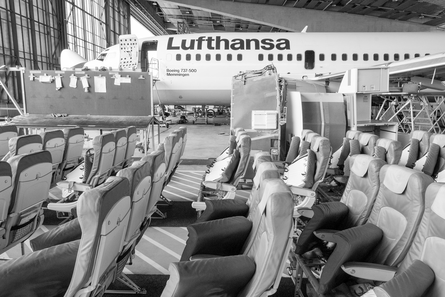 ausgebaute Sitze vor einem Lufthansa Flugzeug im Hangar bei der Wartung